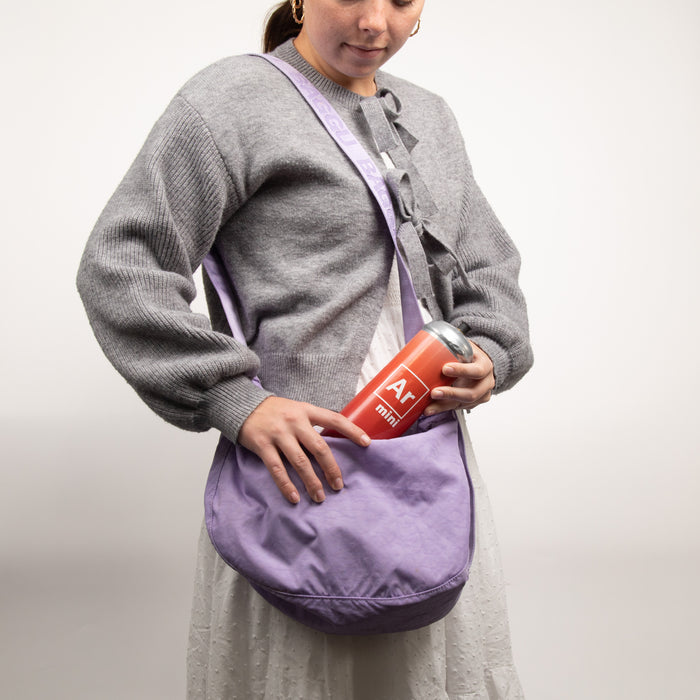 Person wearing a gray sweater and holding a purple bag with a red argon mini tank in it.